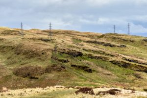 A stock photo of overhead power lines with pylons in rural Scotland