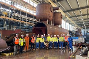 A group of people in high-vis standing in front of a large metal structure in a warehouse